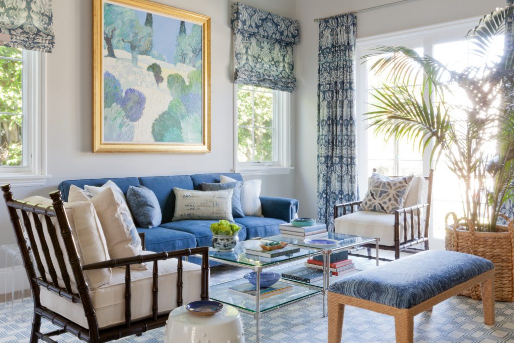 Blue and white roman shades, drapes on chrome rod, uphostered sofa and cushioned rattan chairs