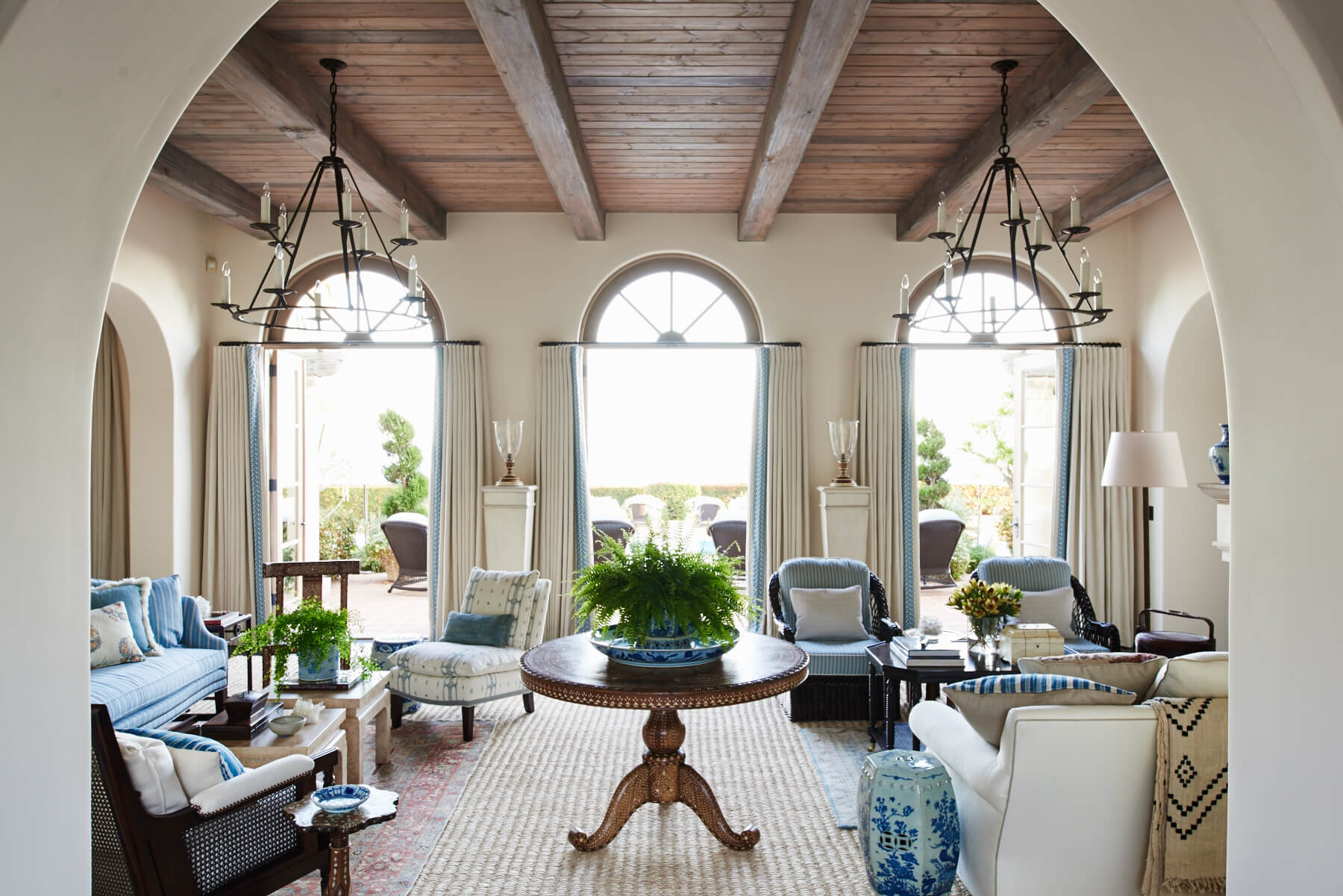 Arched living room with exposed wood ceiling, drapery with custom trim edge and upholstered furniture