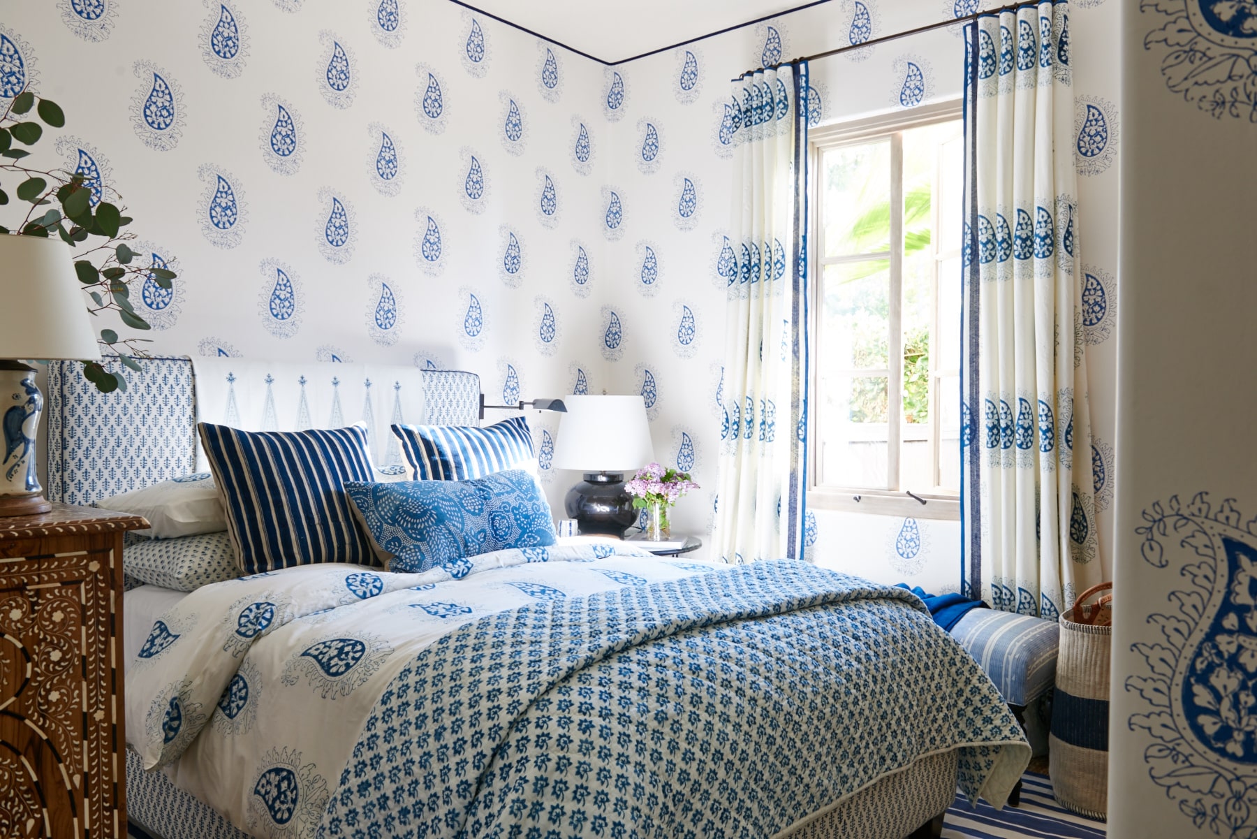 Teardrop pattern blue and white drapery with contrast lead edge, bedding, upholstered headboard, and wallpaper