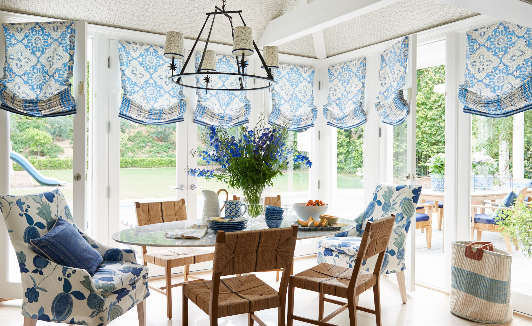 Sunroom blue roman shades and upholstered dining chairs
