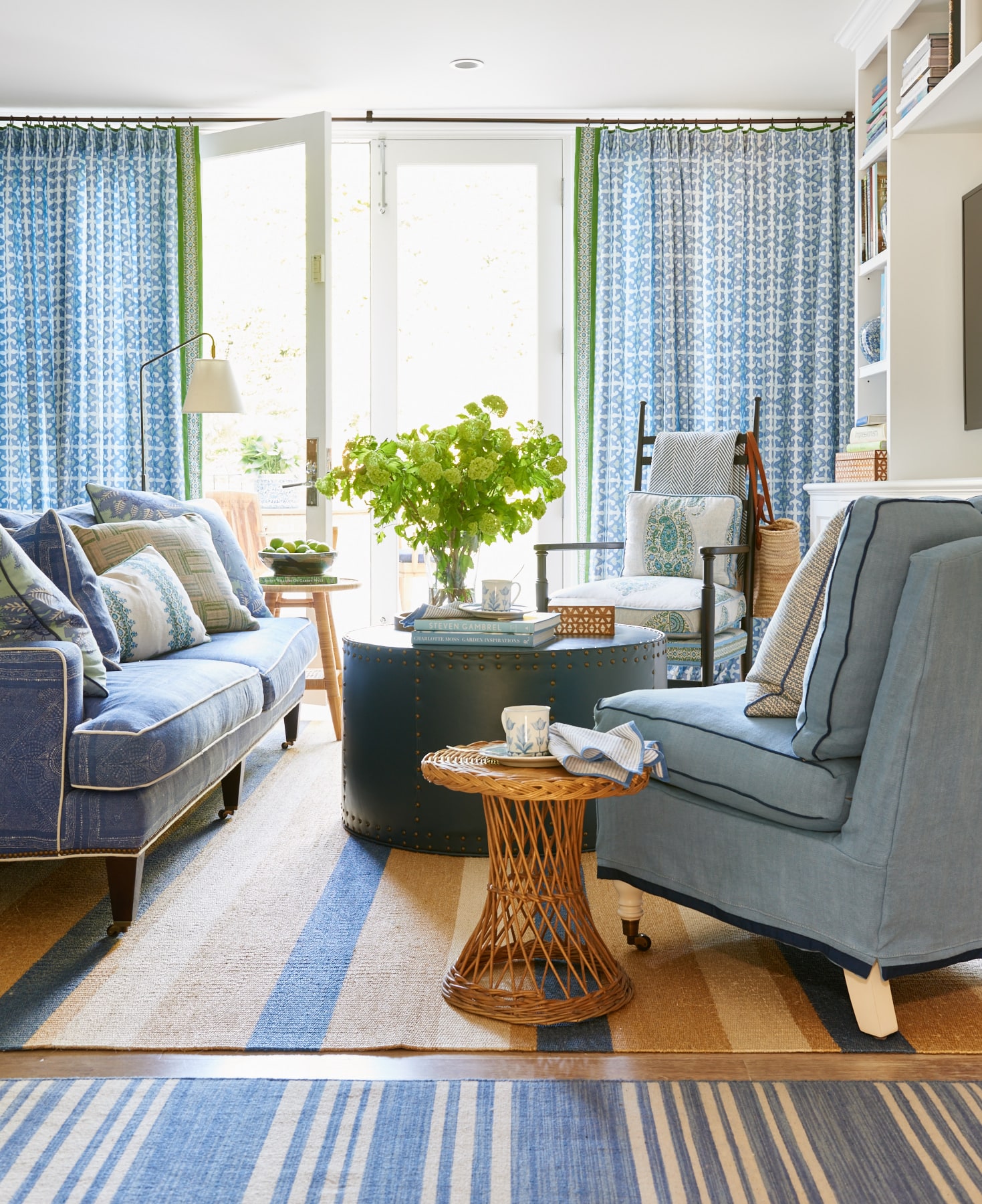 Sheer blue drapes on long iron rod with contrast edge and upholstered seating with contrast trim