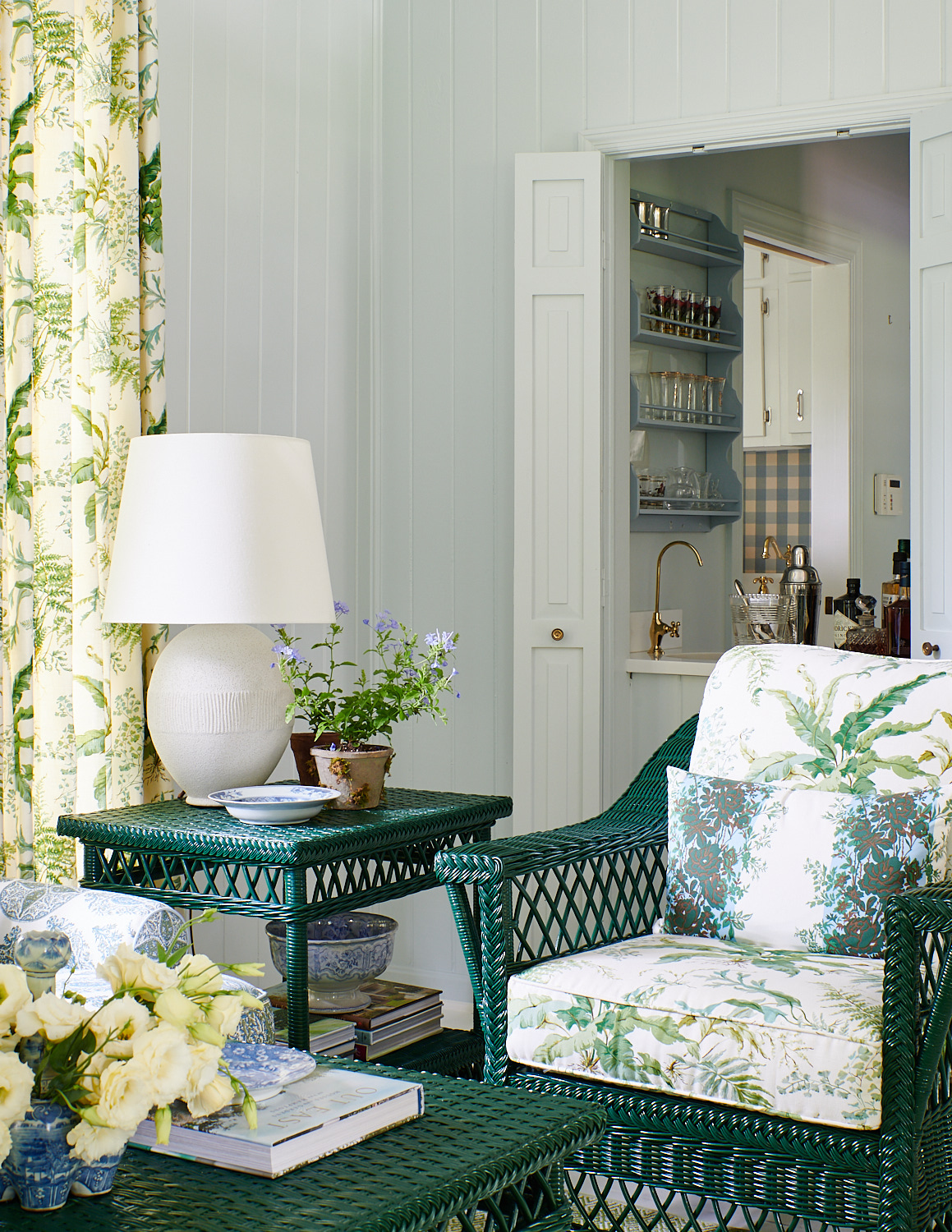 Wide view sun room with floral roman shades, wicker tea chairs with matching cushions and ottomans